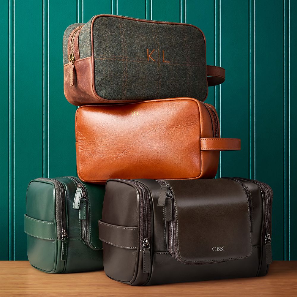 Stack of monogrammed Mark and Graham leather and wool travel pouches in brown, green and tan